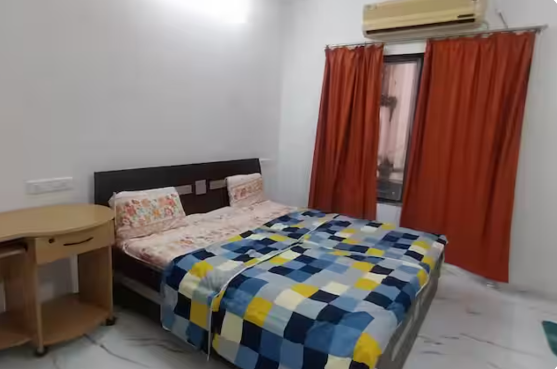 AC bedroom with double bed and orange curtains at AG House