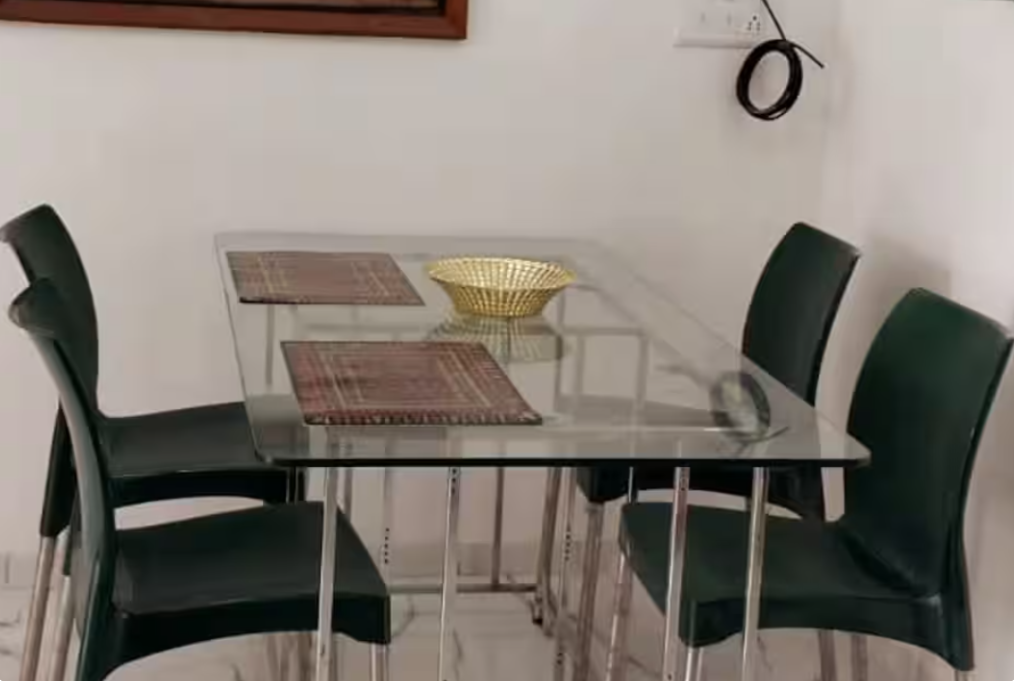 Glass-top dining table with four chairs at AG House